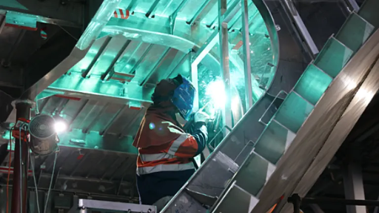 Welder wearing PPE working inside the hull of a vessel