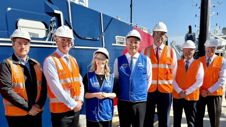 Defence Minister Richard Marles and WA Senator Ellie Whittaker standing on the wharf at Austal's Henderson shipyard with leadership and production team members